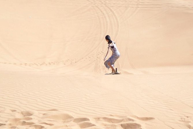 Desert Safari Morning with Camel Ride and Sand Boarding - Sand boarding from a tall dune