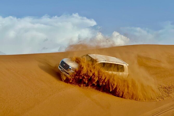 Dubai Desert Safari: Dune Bashing, Camel Ride, Sandsurf & 5<em> BBQ – Key points to know before booking’ /></p>
<ul>
<li><strong>Lahbab’s red dunes provide the main scenery:</strong> Expect a dedicated dune-bashing ride, a sandboarding stop, and a sunset photo break.</li>
<li><strong>The driver matters:</strong> Guides including Ahmed and Ali have been praised for polite service, safety checks, and helping with photographs.</li>
<li><strong>The camp packs in many activities:</strong> Try henna, Arabic dress, camel feeding, falcon posing, coffee, dates, and a short camel ride.</li>
<li><strong>Dinner is part of the package:</strong> The buffet includes vegetarian and non-vegetarian barbecue choices, along with gaymat sweets, gahwa, and dates.</li>
<li><strong>Shows run after dark:</strong> Tanoura, belly dance, fire performance, and Ladies Khaliji Dance are included.</li>
<li><strong>The low price has limits:</strong> The $27.91 rate covers the shared basics, while quad bikes, shisha, alcohol, and VIP tables are separate.</li>
</ul>
<h2>Why Lahbab makes this safari more than a quick sand ride</h2>
<p><img width="669" height="446" decoding="async" src=